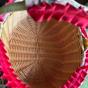 May include: A woven wicker basket with a pink ruffled fabric lining. The basket is empty and the fabric lining is visible.