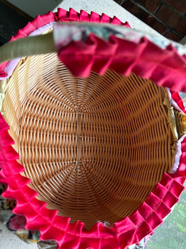 May include: A woven wicker basket with a pink ruffled fabric lining. The basket is empty and the fabric lining is visible.