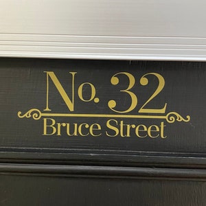 以下が含まれることがあります： 銀色の郵便受けと「No. 32 Bruce Street」という金色の文字が書かれた黒いドア