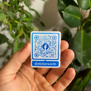 Può includere: Etichetta bianca con un codice QR di Facebook blu e il testo "@stickerworth" sotto.