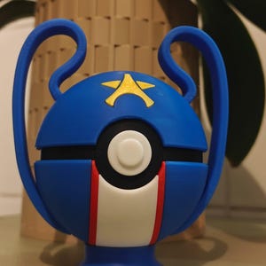 Peut inclure: Une sphère décorative bleue et blanche avec un emblème d'étoile dorée, des rayures rouges et blanches et des poignées bleues. La sphère a un cercle blanc au centre et est probablement un objet décoratif ou un jouet.