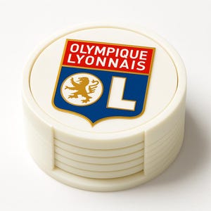 May include: A set of off-white coasters with the Olympique Lyonnais logo. The logo features a gold lion, a blue shield, and the text "OLYMPIQUE LYONNAIS" in red. The coasters are stacked in a holder.