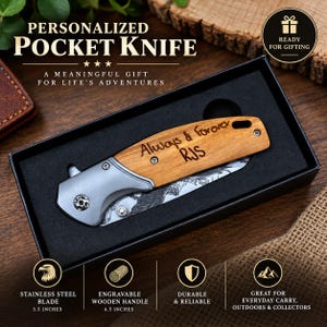 May include: A folding pocket knife with a light brown wooden handle engraved with the text Always & Forever RJS. The knife features a silver-toned metal bolster and a stainless steel blade with a mountain graphic, presented in a black box.