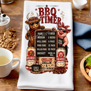 May include: A white kitchen towel featuring a graphic of a highland cow and a pig wearing sunglasses. The text reads BBQ TIMER with a chart listing cooking levels and beer quantities. Two beer cans labeled Moo-Weiser and Oink-Weiser are shown.
