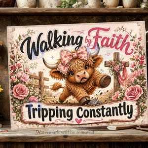 May include: A rectangular sign featuring a brown Highland calf wearing a pink floral bow, positioned between a wooden cross and a fence. The text reads Walking by Faith at the top and Tripping Constantly at the bottom, surrounded by pink roses.