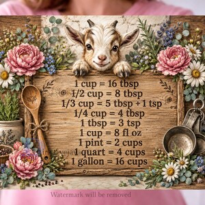 Op de afbeelding: Een houten bord met een geitenillustratie bovenaan en een tabel voor keukenmaten in zwarte tekst. Het bord is versierd met roze pioenrozen, witte madeliefjes, blauwe bloemen, een houten lepel en metalen maatbekers.