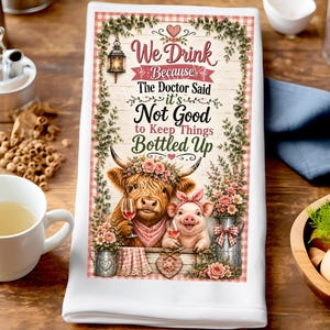 May include: A white kitchen towel featuring a graphic of a Highland cow and a piglet holding wine glasses. The text reads, We Drink Because The Doctor Said it's Not Good to Keep Things BOTTLED UP. The design includes floral accents and a lantern.