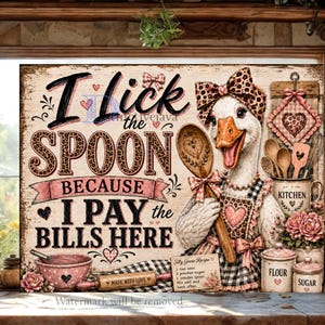 May include: A rustic wooden sign with the text "I Lick the Spoon Because I Pay the Bills Here." It features a goose wearing a chef's hat and apron, holding a wooden spoon. Kitchen-themed decor with pink accents.