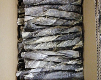 May include: A cardboard box filled with dried fish treats for dogs. The treats are long and thin, and they are arranged in a neat stack.