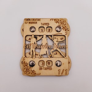 May include: Wooden Elf Warrior Token with a dial for tracking tapped and untapped status. The token features a silhouette of an elf warrior and the text "Elf Warrior Token".