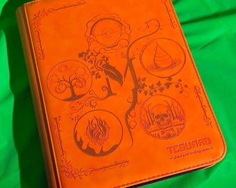 May include: An orange trading card binder featuring an embossed design of four circular elemental icons including a tree, a water droplet, fire, and a skull. The cover includes the text TCGUARD and the phrase guard your trading cards.