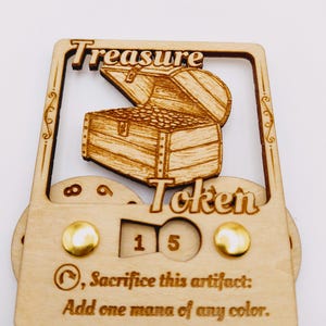 May include: A wooden treasure token with a carved image of a treasure chest. The token has a counter that reads "15" and the text "Sacrifice this artifact: Add one mana of any color."