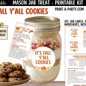 May include: A glass mason jar filled with cookie ingredients, labelled "It's Fall Y'all Cookies." The image includes labels with instructions and a gift idea box. A plate of finished cookies is also present. The jar is approximately 15 cm tall.