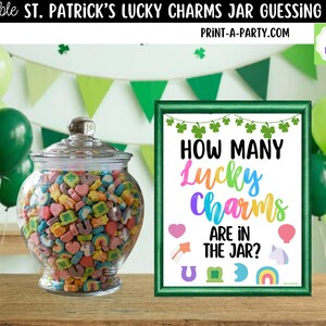 May include: A clear glass jar filled with colorful Lucky Charms cereal, next to a framed sign that reads "How Many Lucky Charms Are In The Jar?" The sign is green with rainbow text and St. Patrick's Day themed graphics. Green balloons and a banner are in the background.