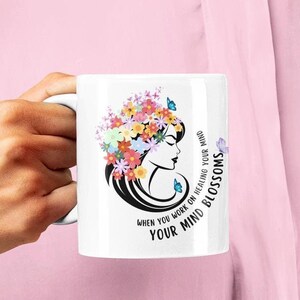 May include: White ceramic mug with a floral design and a woman's face. The text on the mug reads "When you work on healing your mind your mind blossoms."