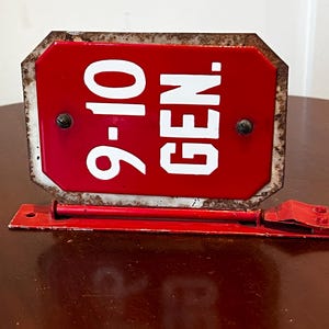 May include: Red metal sign with white lettering that reads "9-10 GEN."