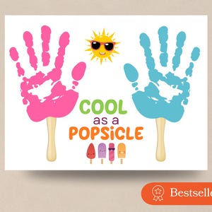 May include: A graphic print featuring a pink handprint and a blue handprint, each attached to a wooden popsicle stick. Between them is a yellow sun wearing sunglasses. The text reads COOL as a POPSICLE, with four small illustrated popsicles below.