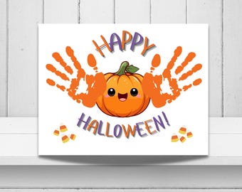 May include: A rectangular print featuring a central orange pumpkin with a smiling face, flanked by two orange handprints. The text HAPPY HALLOWEEN appears in purple and orange letters above and below the pumpkin, with small candy corn icons.