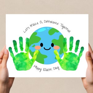 May include: A white card with green handprints on either side of a blue and green cartoon Earth. The Earth has a smiling face and the text "Let's make a difference together" and "Happy Earth Day" are written around the Earth.