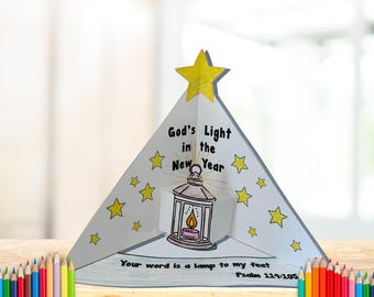 Puede incluir: Una manualidad de papel blanco, triangular, con el texto "God's Light in the New Year" y una ilustración de linterna. La manualidad tiene acentos de estrellas amarillas y la cita "Your word is a lamp to my feet Psalm 119:105".