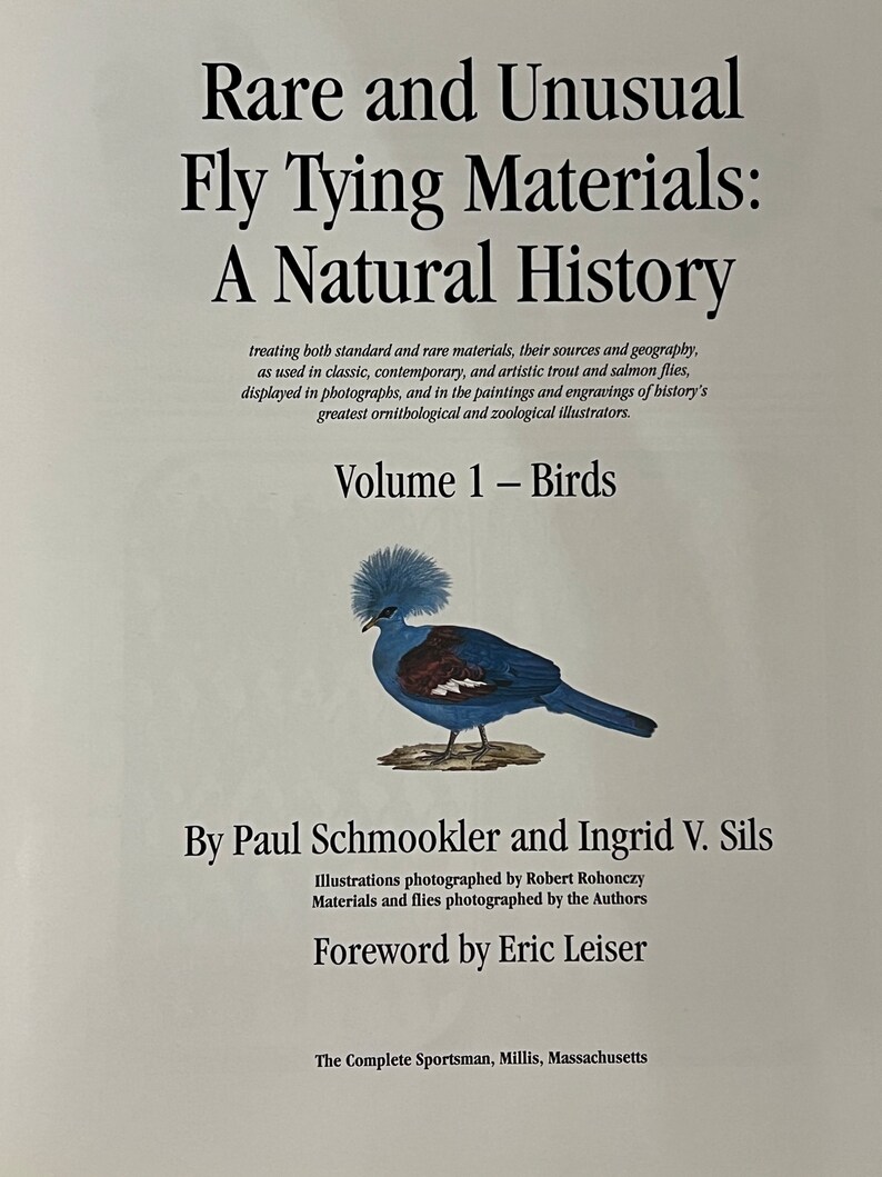 May include: Book cover with the title "Rare and Unusual Fly Tying Materials: A Natural History, Volume 1 - Birds" by Paul Schmookler and Ingrid V. Sils. The cover features an illustration of a blue bird with a crest.