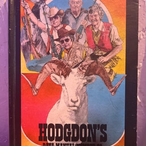 May include: A vintage book cover with a colorful illustration of a bighorn sheep and four people holding rifles. The book title is "Hodgdon's Data Manual Number 22".