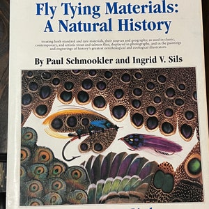 May include: Book cover for "Rare and Unusual Fly Tying Materials: A Natural History, Volume 1 - Birds" by Paul Schmookler and Ingrid V. Sils. The cover features a close-up of colorful feathers and fly-tying materials.