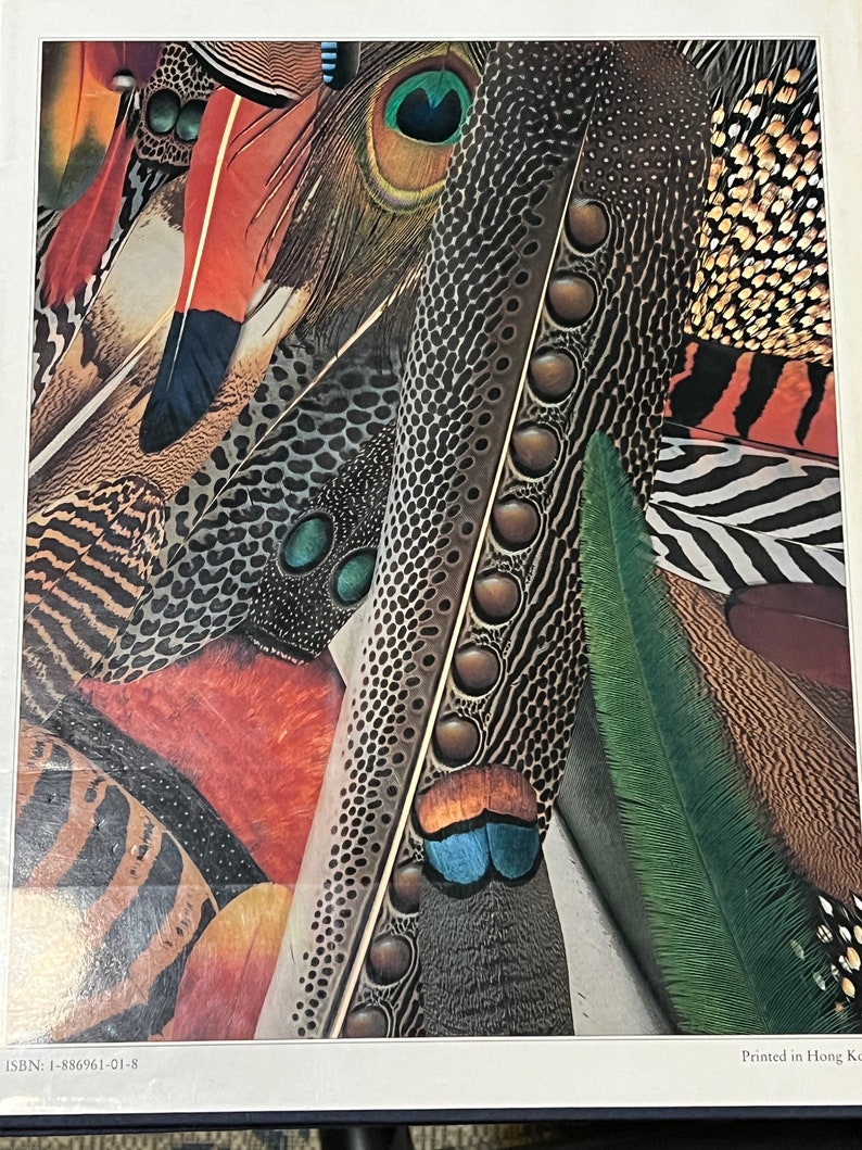 May include: A close-up of a collection of colorful feathers, including peacock, pheasant, and other exotic birds. The feathers are arranged in a pattern, with the tips of the feathers overlapping. The colors are vibrant and rich, with shades of blue, green, red, and brown.