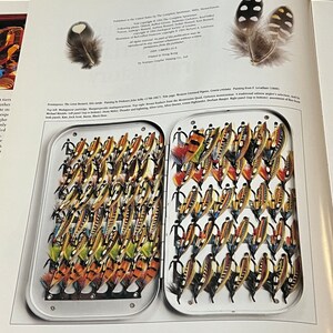 May include: A close-up of a fly fishing tackle box filled with a variety of colorful flies. The box is open and the flies are arranged in rows. The flies are made of feathers, fur, and other materials.