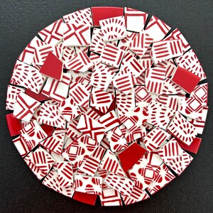May include: A circular collection of ceramic mosaic tiles arranged in a dense pattern. The tiles are primarily white with red geometric designs, including stripes, dashes, and solid red shapes, creating a cohesive, multi-piece decorative surface.