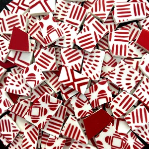May include: A collection of irregular ceramic mosaic tiles featuring a white base with various red patterns, including parallel lines, dashed segments, and geometric shapes. Some tiles are solid red, while others display intricate linear designs.