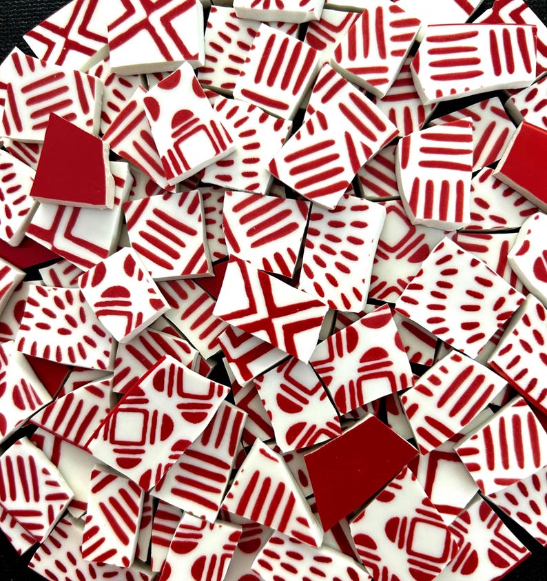 May include: A collection of irregular ceramic mosaic tiles featuring a white base with various red patterns, including parallel lines, dashed segments, and geometric shapes. Some tiles are solid red, while others display intricate linear designs.