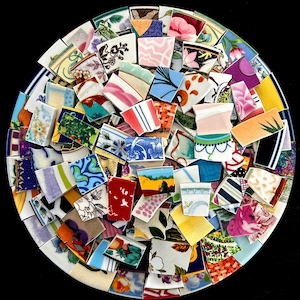 May include: A mosaic of colorful ceramic shards arranged in a circular pattern. The fragments display various patterns, including floral designs, stripes, and abstract shapes, with a mix of colors like blue, pink, yellow, and green. The mosaic is set against a dark background.