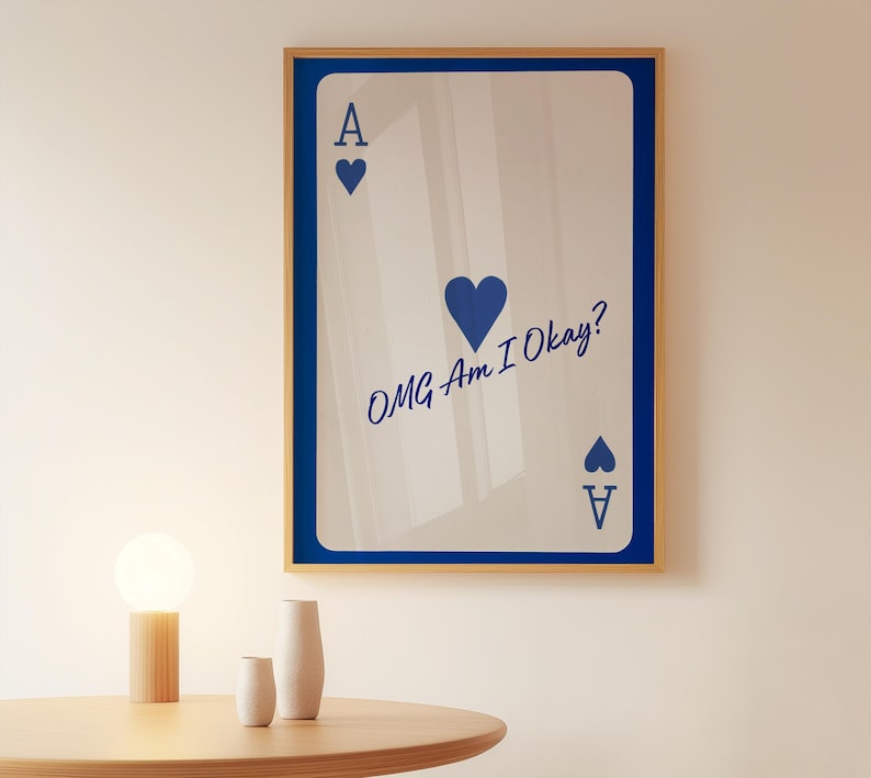May include: Framed wall art featuring a playing card design. The card is white with blue accents, including the Ace symbol and the text "OMG Am I Okay?" The frame is a light wood color with a blue border.