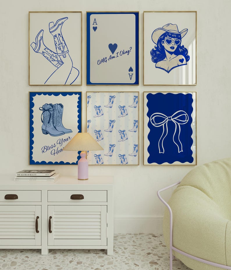 May include: Six framed art prints with blue and white designs. The prints include a pair of cowboy boots, a playing card with text, a cowgirl, a pair of boots with text, a pattern of boots, and a bow. The frames have gold trim.