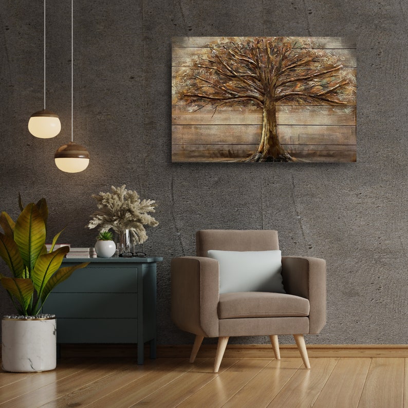 Op de afbeelding: Een bruine fauteuil met een wit kussen staat voor een grijze muur met een houten wanddecoratie met een bruine boom met gouden bladeren.