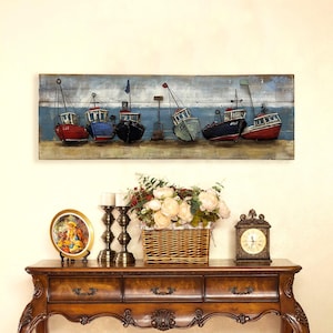 Peut inclure: Une longue &oelig;uvre d'art murale rectangulaire repr&eacute;sentant une rang&eacute;e de bateaux de p&ecirc;che stylis&eacute;s et color&eacute;s sur un fond en bois. Les bateaux sont peints dans des tons de rouge, bleu, vert et noir, avec des accents blancs. L'arri&egrave;re-plan est bleu clair et gris, avec un soup&ccedil;on de nuages blancs. Les bateaux sont dispos&eacute;s en rang&eacute;e, la proue de chaque bateau &eacute;tant tourn&eacute;e vers le spectateur. L'&oelig;uvre d'art est parfaite pour ajouter une touche nautique &agrave; n'importe quelle pi&egrave;ce.