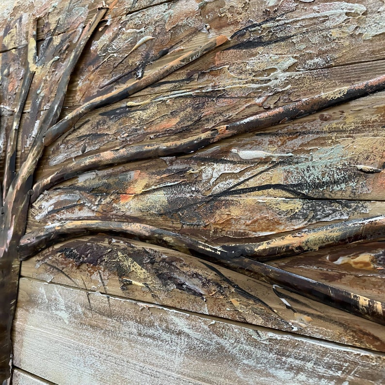 Op de afbeelding: Een getextureerd houten wandkunstwerk met een reli&euml;f, abstract boomontwerp. De takken van de boom zijn geschilderd in tinten bruin, zwart en goud, wat een rustieke en organische uitstraling cre&euml;ert.
