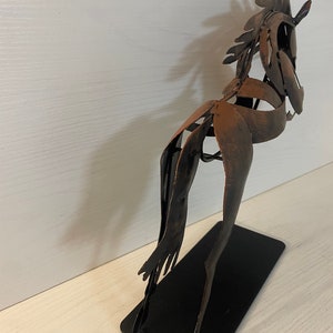 May include: A metal sculpture of a horse in a brown and black finish. The horse is standing on a black metal base.