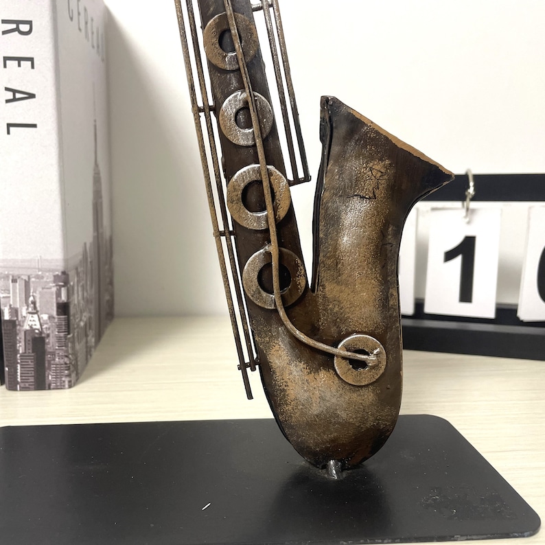May include: A metal saxophone sculpture with a brown and gold finish. The sculpture is on a black base.