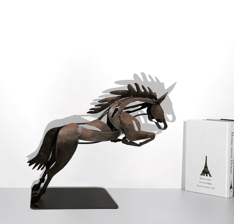 May include: A rusty brown metal sculpture of a horse leaping forward. The horse is on a black base. The sculpture is on a white surface.