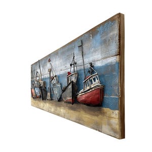Peut inclure: Une &oelig;uvre d'art murale repr&eacute;sentant une rang&eacute;e de cinq bateaux de p&ecirc;che en m&eacute;tal dans diff&eacute;rentes nuances de bleu, rouge et gris, sur un fond en bois bleu et blanc.