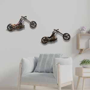 May include: Two metal motorcycle wall sculptures in a living room setting. The motorcycles are brown and black with a distressed finish. The motorcycles are mounted on a white wall.