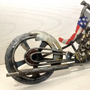 Op de afbeelding: Een metalen sculptuur van een motorfiets met een Amerikaans vlagontwerp. De motorfiets is gemaakt van gerecycled metaal en heeft een robuuste, industri&euml;le uitstraling.
