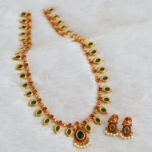 May include: A gold necklace with green and pink stones, and matching earrings. The necklace has a pendant with a larger green stone.