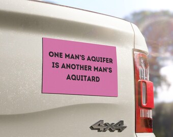 May include: Pink bumper sticker with the text "One man's aquifer is another man's aquitard" on a white truck.