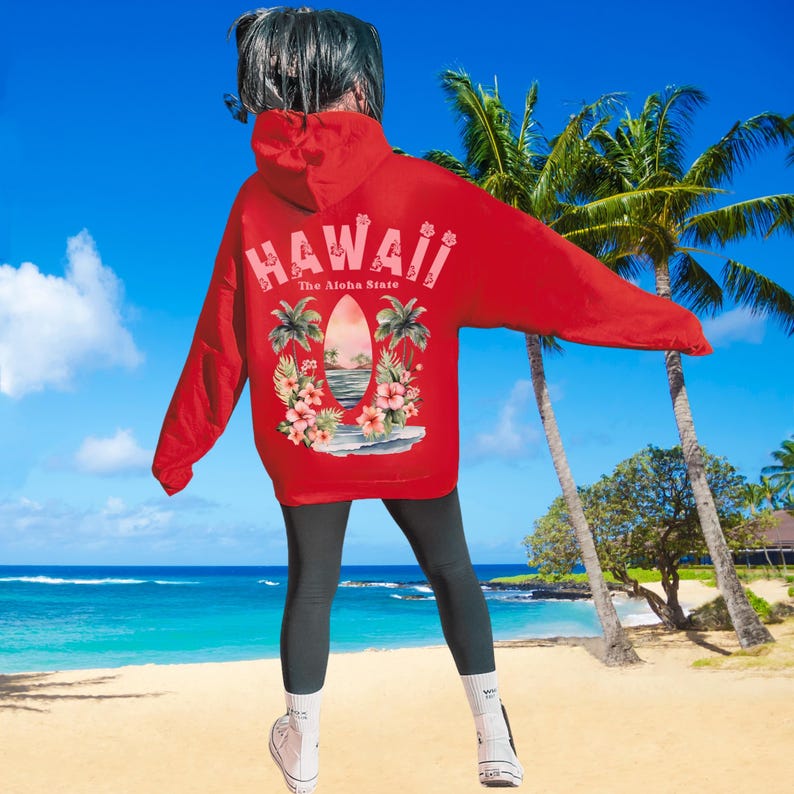 May include: A red hoodie with the word "HAWAII" in pink letters across the back, along with a graphic of a surfboard, palm trees, and flowers. The text "The Aloha State" is below the word "HAWAII".