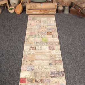 May include: A rectangular patchwork rug with a beige border and various muted colours. The rug is made of rectangular fabric pieces, each with a unique pattern. The rug is approximately 90 cm wide and 240 cm long.