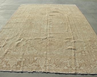 May include: A large rectangular area rug featuring a monochromatic beige and tan color palette. The rug displays an intricate, woven geometric and floral pattern throughout its surface, complete with a detailed border and short fringe at the edges.