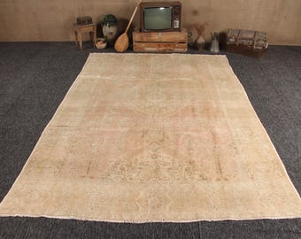 May include: A large rectangular area rug featuring a faded, muted peach and beige color palette. The rug displays a central medallion design surrounded by intricate, low-contrast floral and geometric patterns with a fringed edge on both ends.